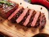 Grilled striploin sliced steak on cutting board over stone table