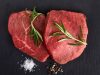Raw beef steaks with rosemary Fresh raw beef with rosemary on black background